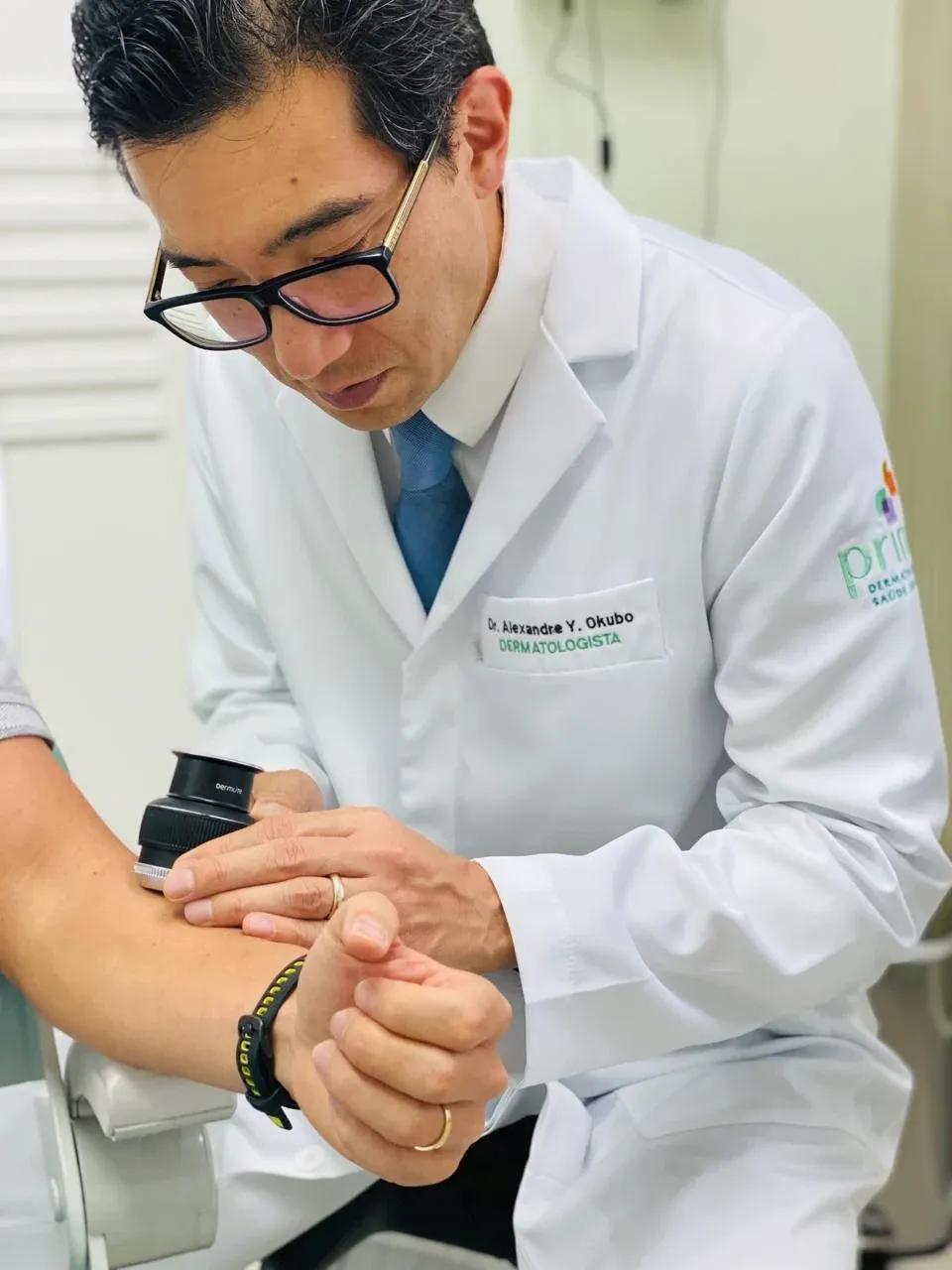 Dr. Alexandre Okubo examinando uma pinta no braço de um paciente com dermatoscópio